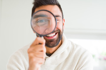Fototapeta na wymiar Handsome man using magnifying glass, doing funny faces