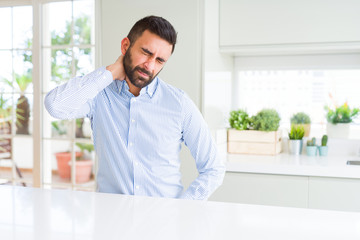 Handsome hispanic business man Suffering of neck ache injury, touching neck with hand, muscular pain