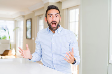 Fototapeta premium Handsome hispanic business man celebrating crazy and amazed for success with arms raised and open eyes screaming excited. Winner concept