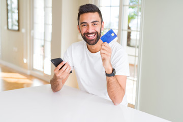 Handsome man using credit card to pay online with smartphone