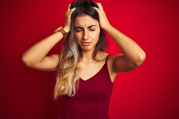 Young beautiful woman wearing a t-shirt over red isolated background suffering from headache desperate and stressed because pain and migraine. Hands on head.