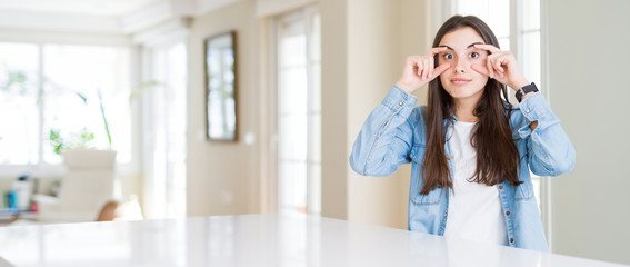 Wide angle picture of beautiful young woman sitting on white table at home Trying to open eyes with...