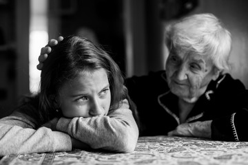 A little girl cries, her grandmother pats her hand on the head. Black and white photo.