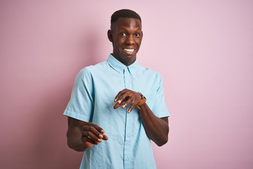 African american man wearing blue casual shirt standing over isolated pink background disgusted expression, displeased and fearful doing disgust face because aversion reaction. With hands raised. 