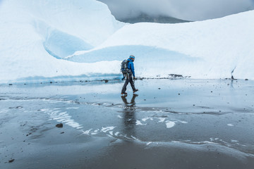 Man walking across flat muddy section of glacier ice on the Matanuska Glacier.