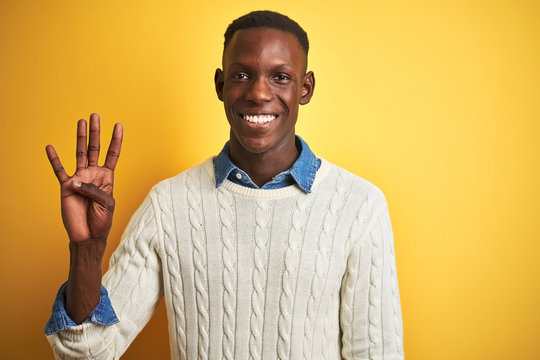 African american man wearing denim shirt and white sweater over isolated yellow background showing and pointing up with fingers number four while smiling confident and happy.