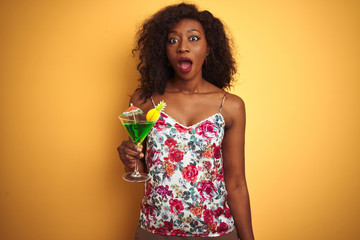 Young african american woman drinking cocktail standing over isolated yellow background scared in shock with a surprise face, afraid and excited with fear expression