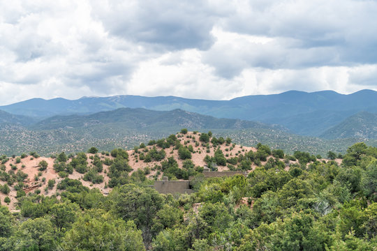 Cloudy evening sunset in Santa Fe, New Mexico mountains in Tesuque community neighborhood with house green plants and blue stormy sky
