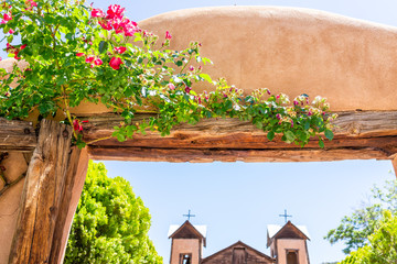 Famous El Santuario de Chimayo sanctuary church in the United States with entrance gate closeup of flowers in summer