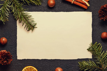 Christmas composition, blank for greeting card or other design - old paper with a Christmas tree branch and decorations on a dark background, flat lay, top view, copy space, place for text