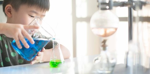 Kid learning science in chemical laboratory.