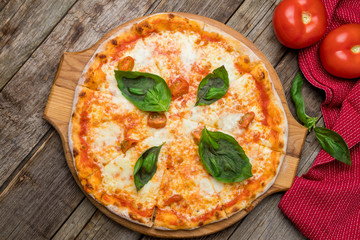 Italian pizza Margherita with basil on wooden background