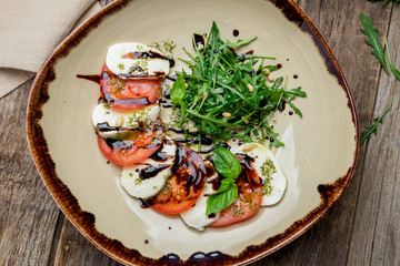 Caprese salad with mozzarella and tomato on old wooden table