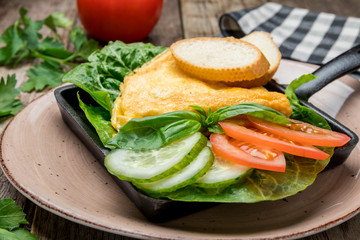 omelette breakfast on plate with vegetables on old wooden table