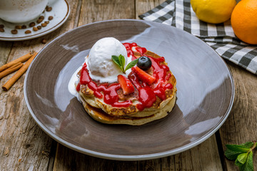 Pancakes with berries and ice cream on old wooden table