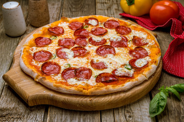 Pepperoni pizza on board on old wooden table