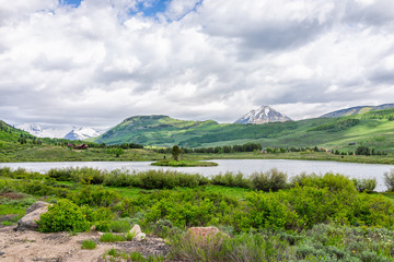 Crested Butte, Colorado alpine peanut lake on hiking trail in summer on cloudy day with green grass and mountain view