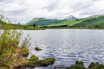 Crested Butte, Colorado alpine peanut lake water on lower loop hiking trail in summer on cloudy day with green grass and mountain view