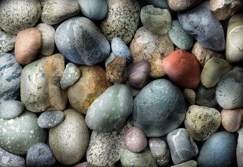 Various stones rounded by wave action on shoreline of lake.