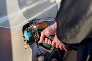 A man hand holding pump filling gasoline. Pumping petrol into the tank. A car refuel on gas station