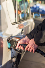 A man hands holding pump filling gasoline. Pumping petrol into the tank. A car refuel on gas station