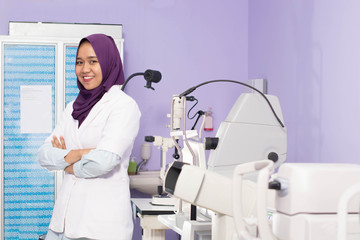 Fototapeta premium Attractive Female muslim Hijab Ophthalmologist doing eye examination to her male patient with digital Tonometer inside her clinic