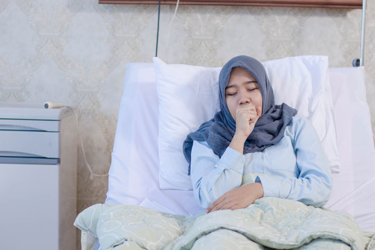 Beautiful Arabic Asian Female Muslim rest on the hospital bed room have cough feel unwell