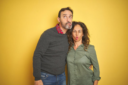 Beautiful Middle Age Couple Over Isolated Yellow Background Making Fish Face With Lips, Crazy And Comical Gesture. Funny Expression.