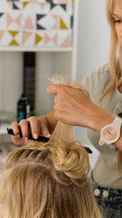 Naklejka premium Hairtician builds upper bun. Hairstyle on bob. Hairdressing services. Creating evening hairstyles fashionable stylish women's hairstyles. Process of hair styling. Courses in hairdressing. Beauty salon