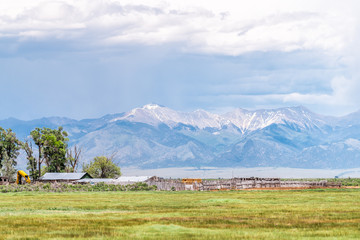 Colorado route road 285 with rural farm pasture and wooden house near Center and Monte Vista and view of Rocky Mountains © Kristina Blokhin