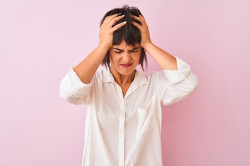 Young beautiful woman wearing white shirt standing over isolated pink background suffering from headache desperate and stressed because pain and migraine. Hands on head.