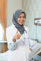 portrait of attractive hijab female doctor standing and smiling at camera