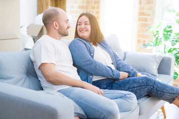 Fototapeta na wymiar Young couple in love relaxing and hugging sitting on the sofa at new home, smiling very happy for moving to a new apartment