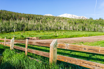 Closeup of wooden fence in parking lot in morning at Thomas Lakes Hike in Mt Sopris, Carbondale, Colorado with road and nobody view of snow mountain