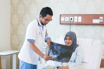 Fototapeta premium Portrait of Asian male doctor with his female patient in the hospital clinic explaining xray results