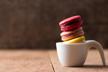 Pile of sweet and colourful french macaroons on wood background.