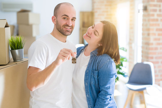 Young couple smiling very happy showing keys of new home, moving and buying new apartmet concept