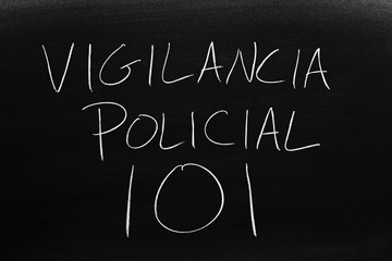 The words Vigilancia Policial 101 on a blackboard in chalk.  Translation: Policing 101