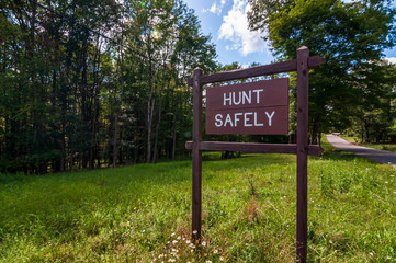 A wooden sign saying HUNT SAFELY on the side of a road in Warren county, Pennsylvania, USA on a...