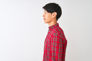 Young chinese man wearing casual red shirt standing over isolated white background looking to side, relax profile pose with natural face with confident smile.