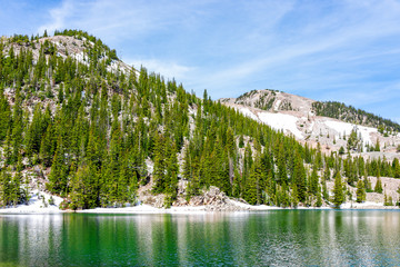 Pine tree forest and emerald green alpine lake water color on Thomas Lakes Hike in Mt Sopris, Carbondale, Colorado