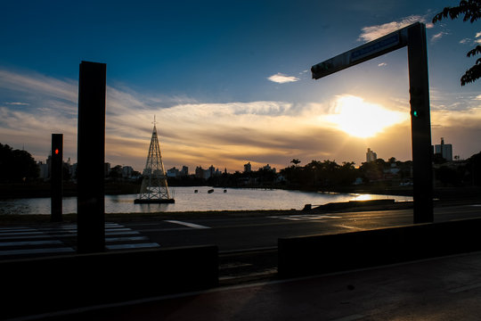 P&ocirc;r do sol na represa de S&atilde;o Jos&eacute; do Rio Preto, com raios de sol iluminando as silhuetas das constru&ccedil;&otilde;es, ruas e sem&aacute;foro