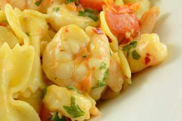Shrimp and farfalle pasta with tomatoes in white serving dish