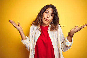 Young beautiful woman wearing red t-shirt and stripes shirt over yellow isolated background...
