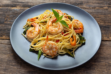 Spaghetti with spicy fried shrimp on a wooden table