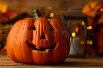 Halloween pumpkin head jack lantern on a wooden background with blurry lights, background for the holiday