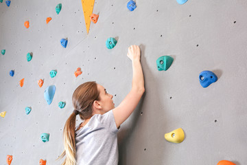 Fototapeta premium Young woman climbing wall in gym
