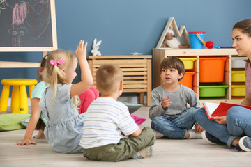 Nursery teacher with cute little children in kindergarten