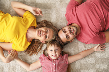 Portrait of happy young family lying on carpet at home