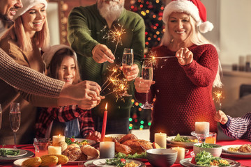 Happy family with Christmas sparklers and glasses of champagne at home